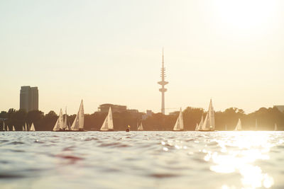 Water surface image of boats moving on river against sky during sunset