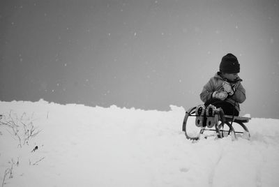 Boy sitting on sled over snow