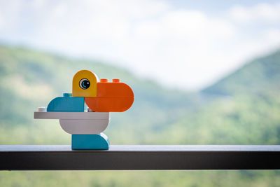 Close-up of stuffed toy on railing against sky