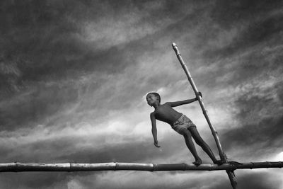 Low angle view of boy jumping against sky