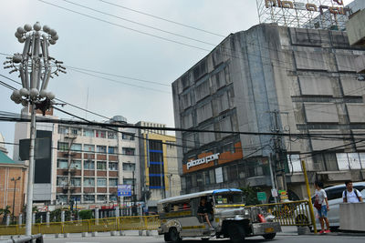 People on city street by buildings against sky