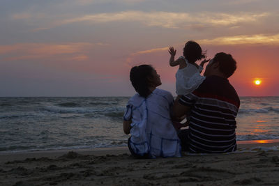 Rear view of couple on beach during sunset