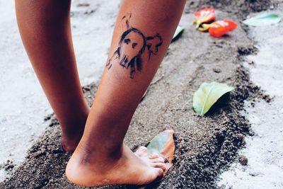 Low section of woman with human skull drawing on leg