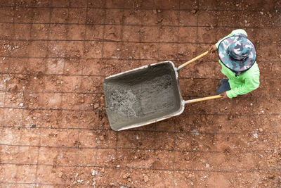 High angle view of man pushing wheelbarrow on footpath