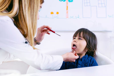 Female doctor examining boy tongue in hospital