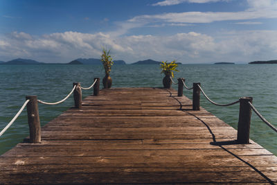 Wooden boardwalk leading towards sea against sky