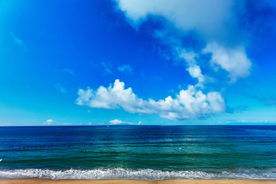 Scenic view of sea against sky with group of surfers