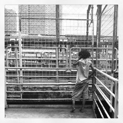 Rear view of boy standing against railing