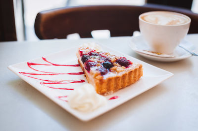 High angle view of pastry with cappuccino served on table