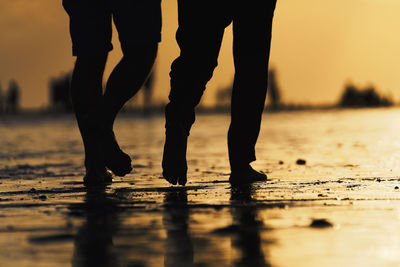 Low section of silhouette people standing on beach