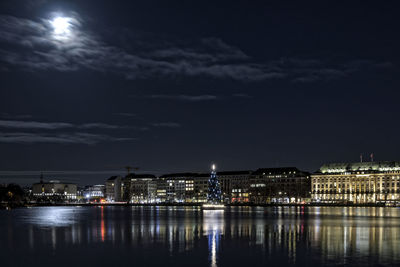 Illuminated christmas tree in binnenalster lake by city at night