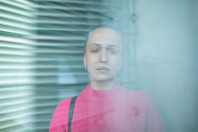 Portrait of beautiful young woman standing against wall