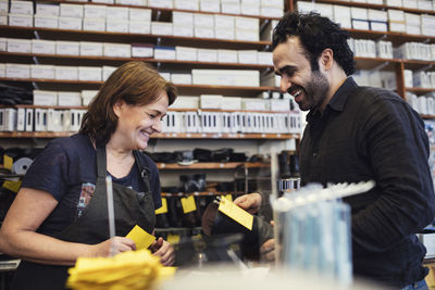 Happy customer talking with shoemaker at repair shop