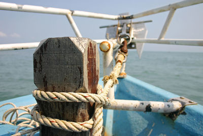 Close-up of rope tied to railing of boat on sea