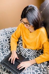 Midsection of woman using a laptop at home while staying warm with a blanket