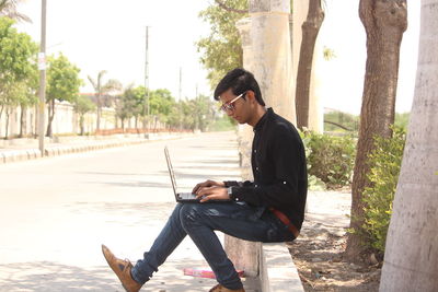 Side view of young man using mobile phone