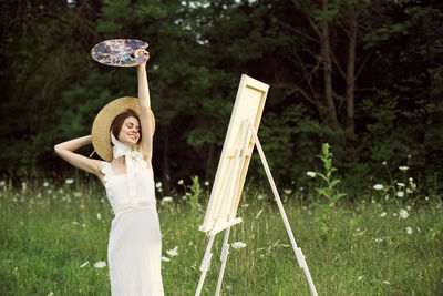 Portrait of young woman standing against trees