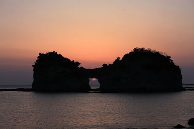 Rock formations in sea against sky during sunset