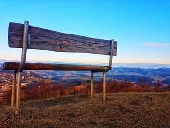 Empty bench on field against sky