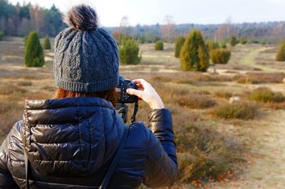 Rear view of woman photographing on field