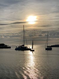 Silhouette sailboats on sea against sky during sunset