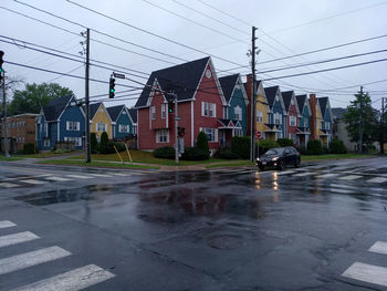 Wet street by buildings in city during rainy season