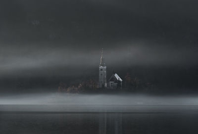 Church reflecting on lake against sky at night