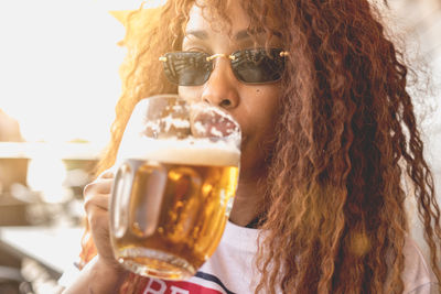 Portrait of young woman drinking beer in glass