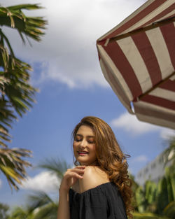 Low angle view of smiling woman standing against sky