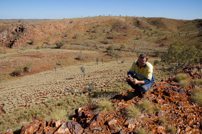 Full length of man crouching on field against clear sky