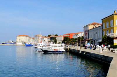 Boats at harbor in piran against sky