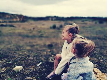 Mother and daughter on grass against sky