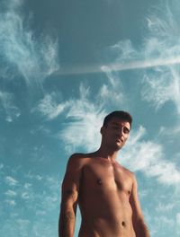 Low angle view of shirtless man looking away against sky