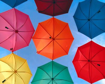 Low angle view of multi colored umbrellas hanging against blue sky