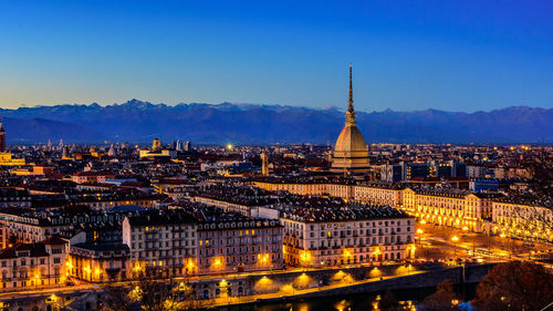 High angle view of illuminated cityscape against clear blue sky