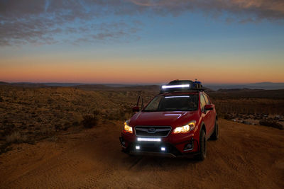 Vintage car on land against sky during sunset