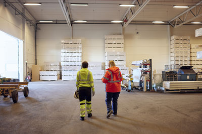 Rear view of multiracial female colleagues walking in distribution warehouse