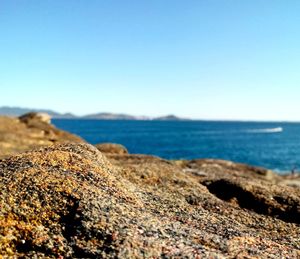 Rocks on beach against clear blue sky