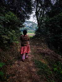 Rear view of woman walking in forest