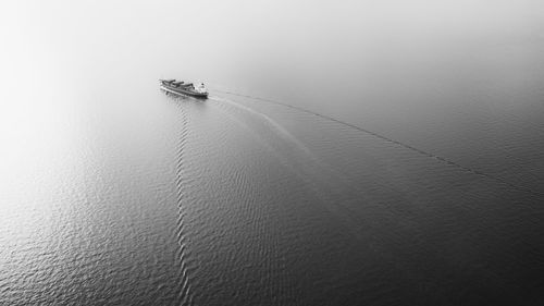 Black and white smaller container ship sailing in sea and beautiful streak sea waves background 