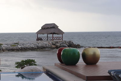 Lounge chairs and table at beach against sky