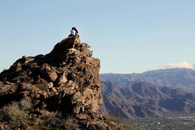 Couple sitting on mountain top in desert embracing