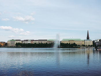 Fountain in river against buildings in city