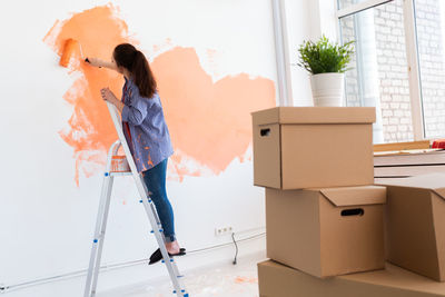 Young woman painting wall at home