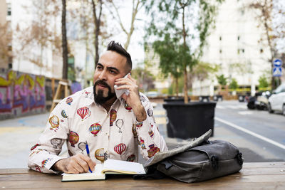 Young bearded businessman sitting at table,using mobile phone