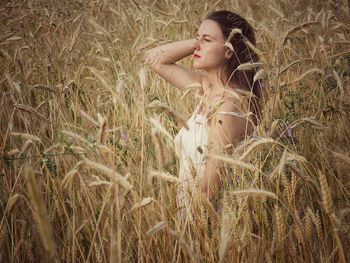 Side view of young woman looking away while standing at farm