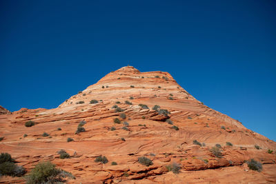 Low angle view of rock formations against clear blue sky