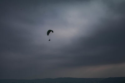 Low angle view of silhouette paragliding against sky