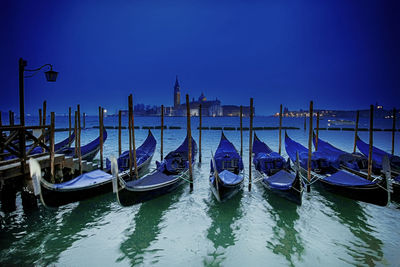 Boats moored in canal against clear sky