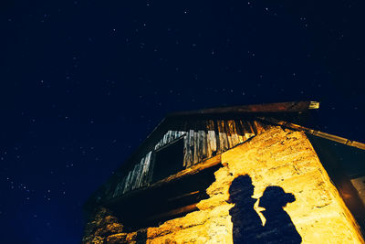 Low angle view of couple shadow on house against sky at night